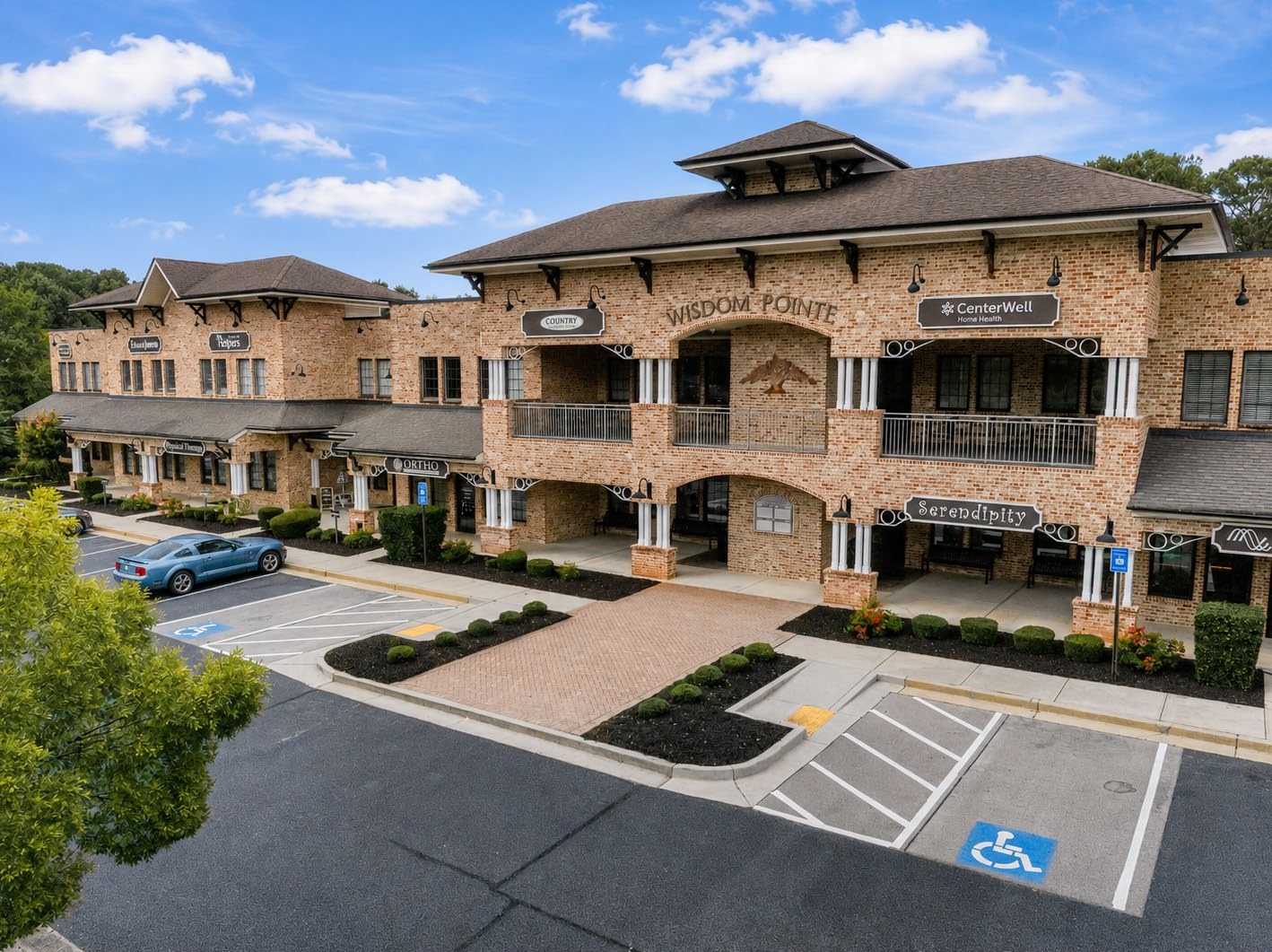 Angled exterior view of Wisdom Pointe Village showing the full three-story façade and parking field
